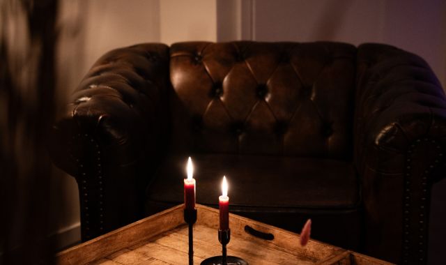 Auf einem kleinen Tisch stehen zwei Kerzen. Im Hintergrund ist ein Sofa