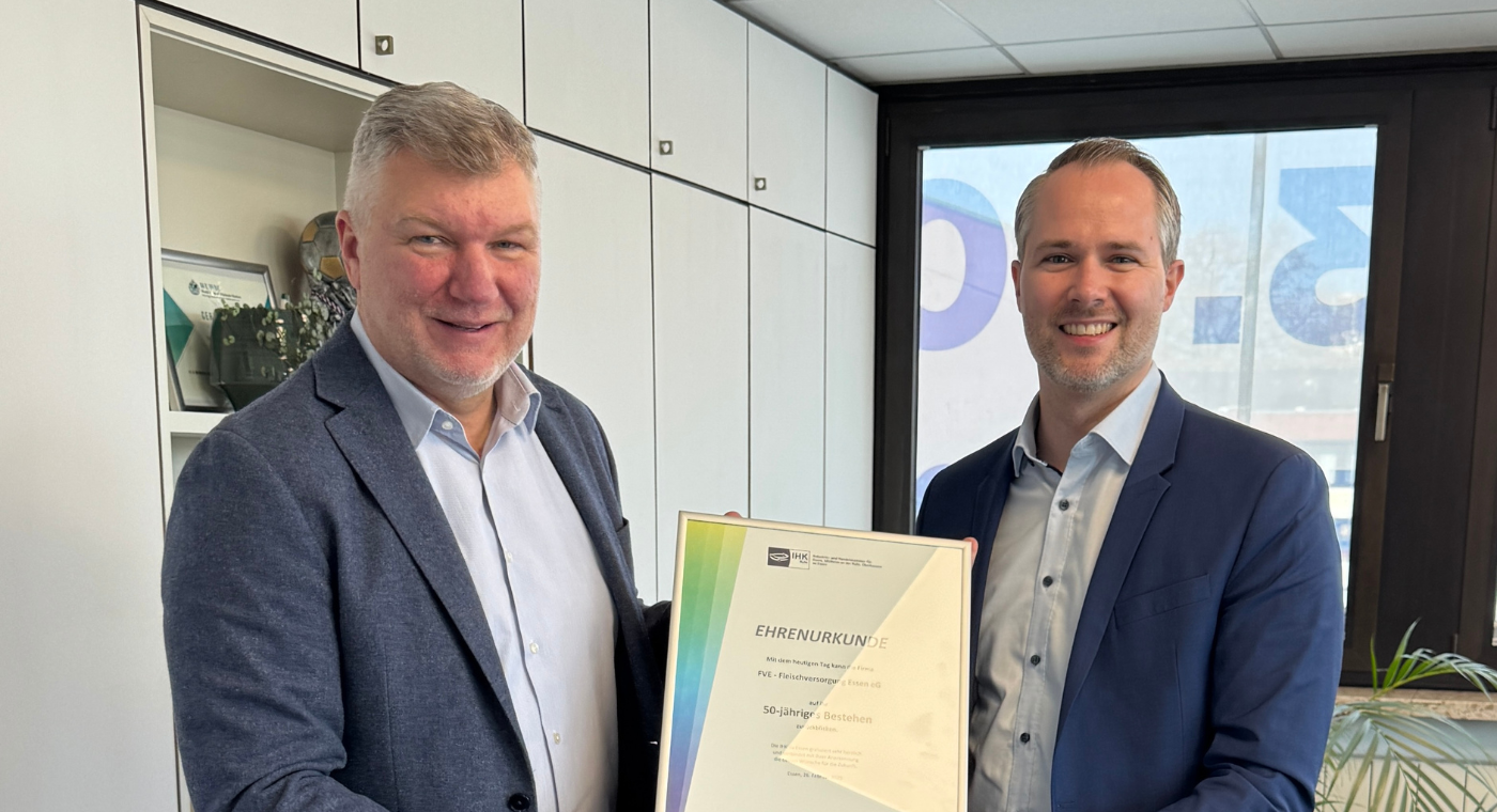 Zwei Männer halten eine Urkunde und schauen in die Kamera.