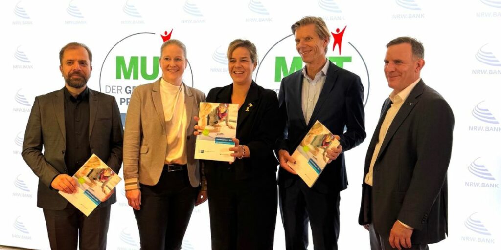 Vier Personen stehen nebeneinander und lächeln.