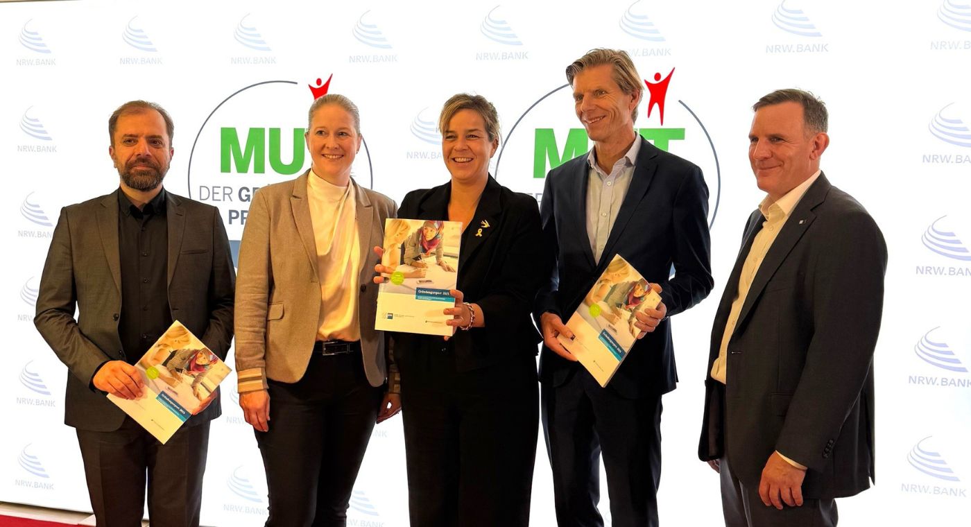 Vier Personen stehen nebeneinander und lächeln.