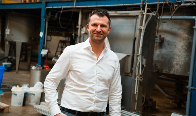 Ein Mann in einem weißen Hemd steht in einer Fabrikhalle.