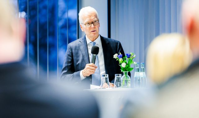 Ein Mann im Anzug hält ein Mikrophon.