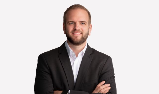 Ein Mann im Anzug lächelt in die Kamera.