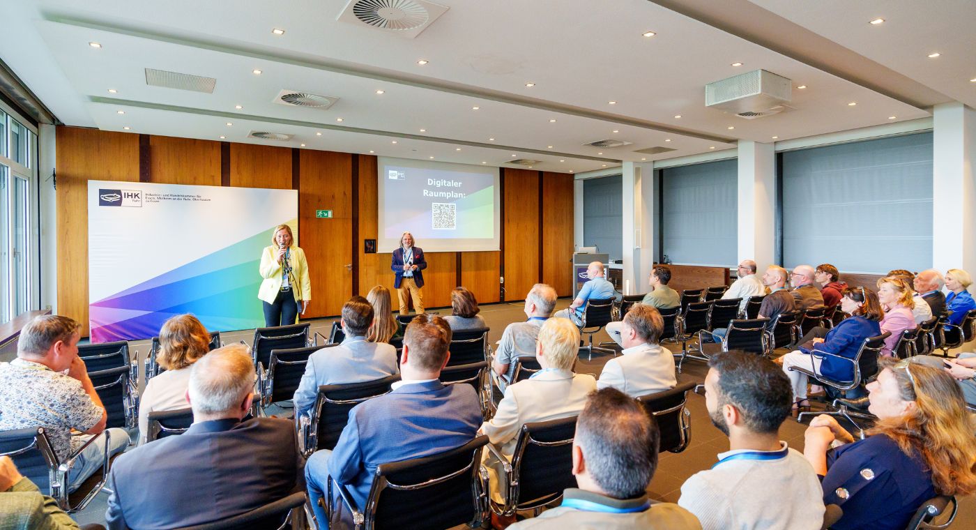 Die Hauptgeschäftsführerin der IHK zu Essen hält ein Mikrofon in der Hand und spricht für eine Gruppe von Personen.