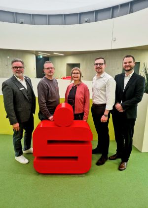 Gruppenfoto von 5 Personen. In der Mitte steht das Sparkassen-Logo.