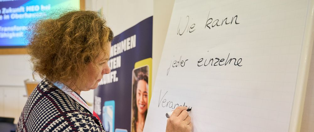 Eine Frau schreibt etwas auf eine Tafel.