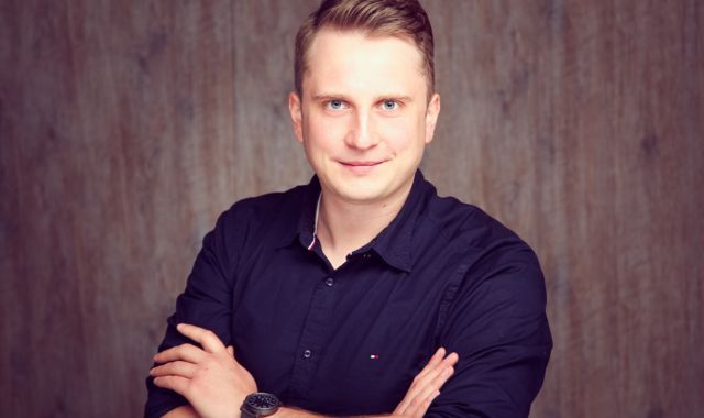 Ein Mann hat die Arme verschränkt und schaut in die Kamera.