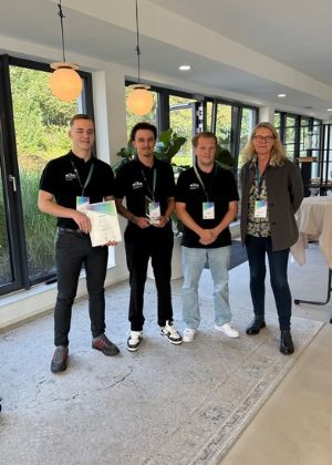 Gruppenfoto von vier Personen. Einer von ihnen hält eine Urkunde in der Hand.