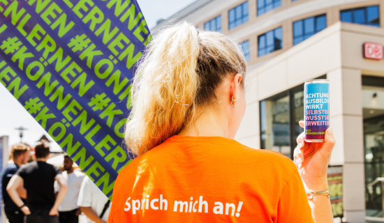 Frau zeigt Energy-Drink mit #Könnenlernen.